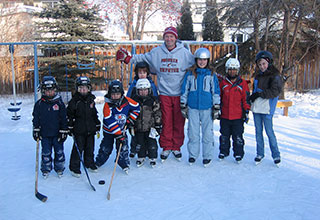 Image of Wayne with children on homemade rink.